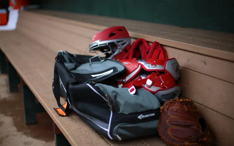 How to Maintain Sports Equipment: A Complete Care, Storage, and Hanging Guide | Heavy Duty Hangers by Tough Hook Baseball glove, catcher's mitt, and batting helmet on a bench ready for a pre-use safety check