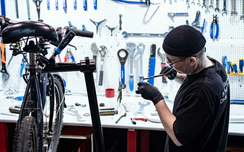 How to Maintain Sports Equipment: A Complete Care, Storage, and Hanging Guide | Heavy Duty Hangers by Tough Hook Mechanic repairing a bicycle in a workshop as part of sports gear maintenance