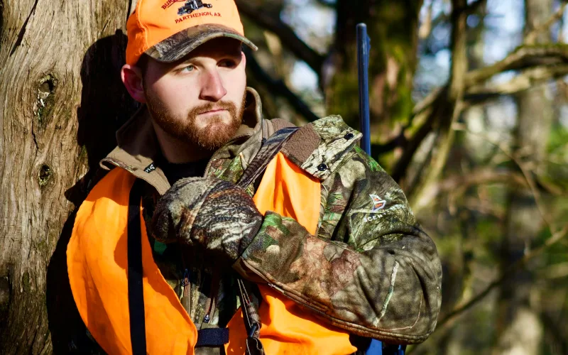 Why a RHINO Hanger is Your Secret Weapon for Organizing Your Hunting Gear | Heavy Duty Hangers by Tough Hook Hunter in camouflage and blaze orange carrying an organized hunting backpack