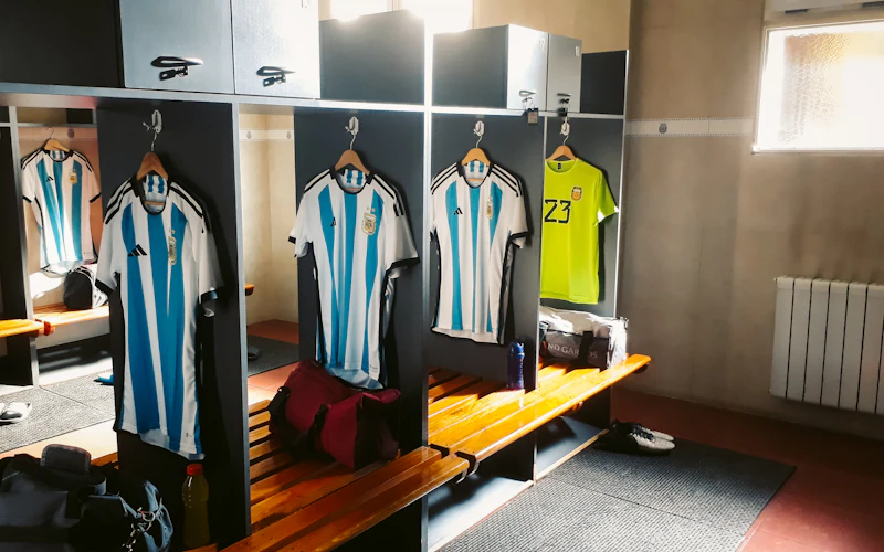 Use a Hanger to Declutter Football Gear in Locker Rooms | Heavy Duty Hangers by Tough Hook Team jerseys hanging on hangers inside open locker room stalls