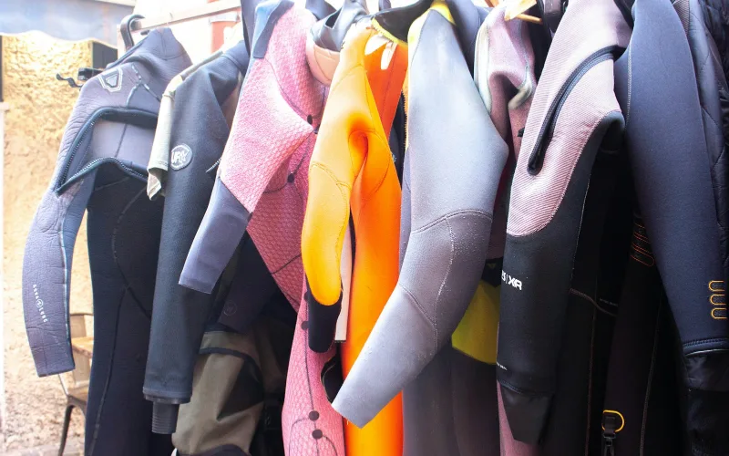 Dry Faster, Smell Less: Better Hanging for Damp or Sweaty Gear | Heavy Duty Hangers by Tough Hook Wetsuits hanging on a rack to dry in a shaded, well-ventilated area after a dive